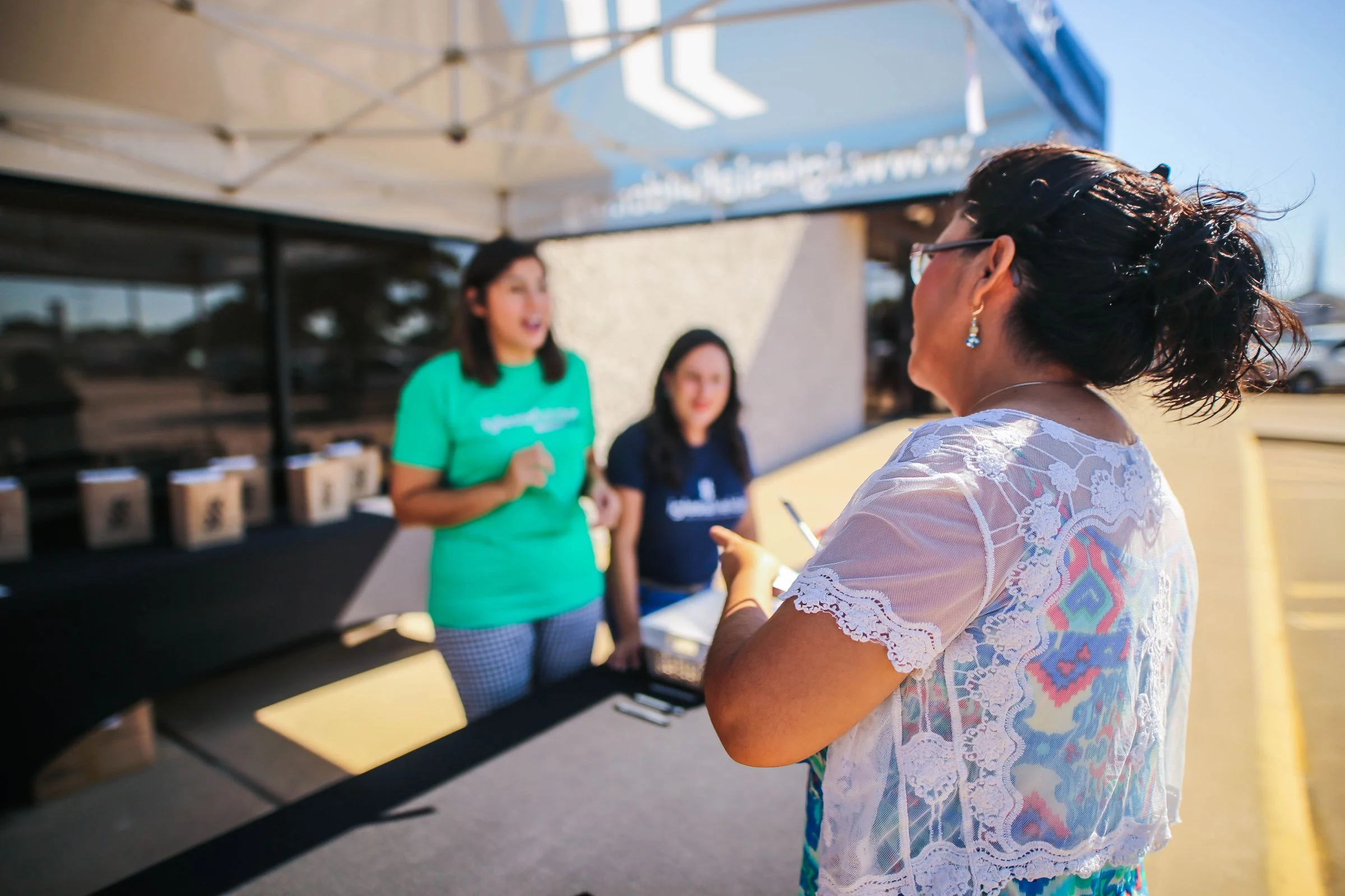 People talking at an outdoor community event registration table
