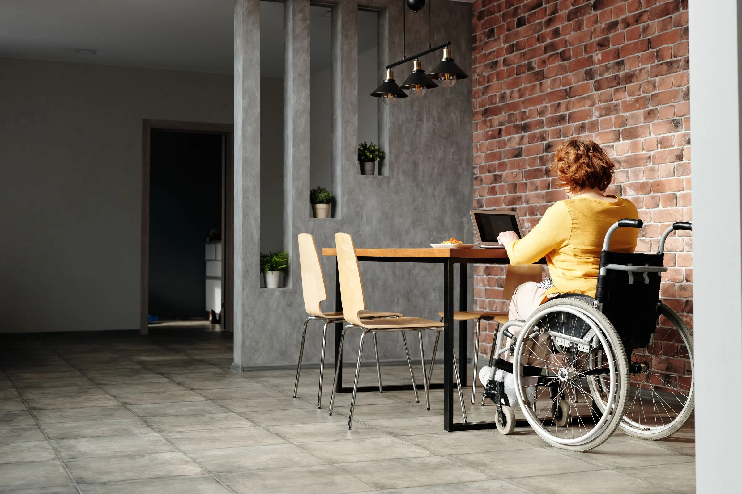 A woman using a wheelchair working on a laptop at home