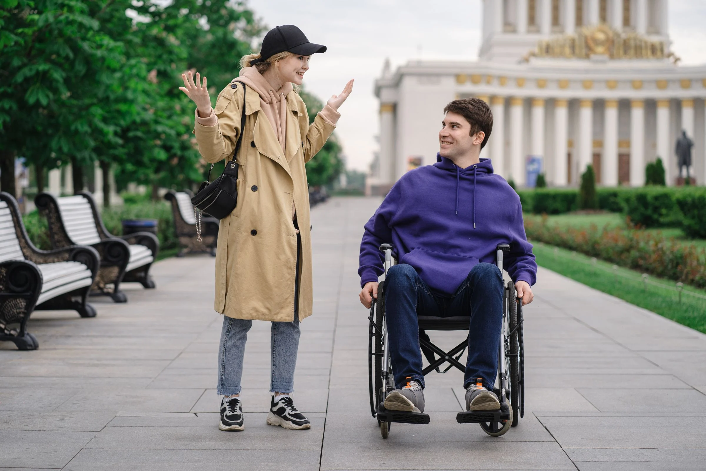 Two people having a conversation in a park, one using a wheelchair
